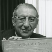 Max Fisher poses with a plaque from an article from The Detroit News about his involvement with the renaissance of Detroit.