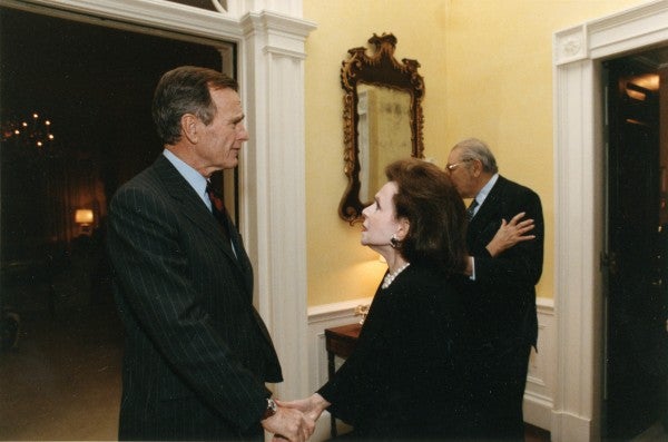 Marjorie Fisher shakes hands with George H. W. Bush, as Max M. Fisher greets Barbara Bush in the background.