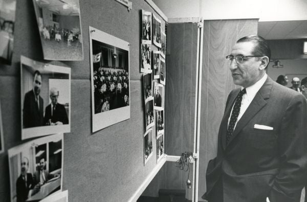 Max Fisher looking at a wall of photographs in 1961.